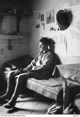 portrait-of-20555-sapper-eric-keast-burke-1st-australian-wireless-signal-squadron-reading-a-book-sitting-on-his-bed-in-a-corner-of-his-billet