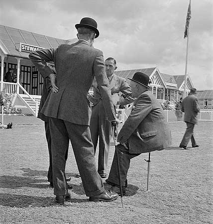 view-of-a-group-of-officials-talking-one-seated-on-a-shooting-stick-outside-the-stewards-building-at-the-royal-show-windsor-photographer-john-gay-date-taken-jul-1954