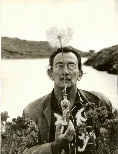 Dali holding the Dandelion flower, symbol of knowledge. Photo by Robert Descharnes, Port Lligat, Spain, October 11, 1959