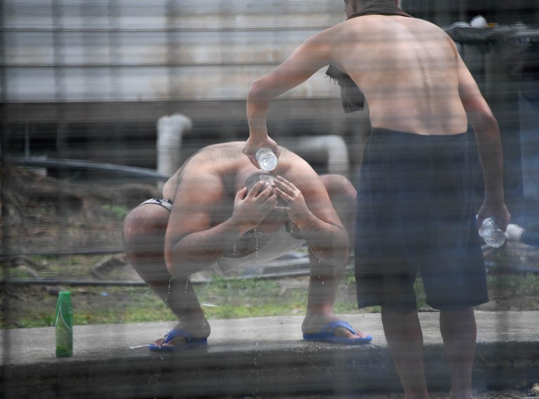 Asylum seekers wash and cool down with precious well water